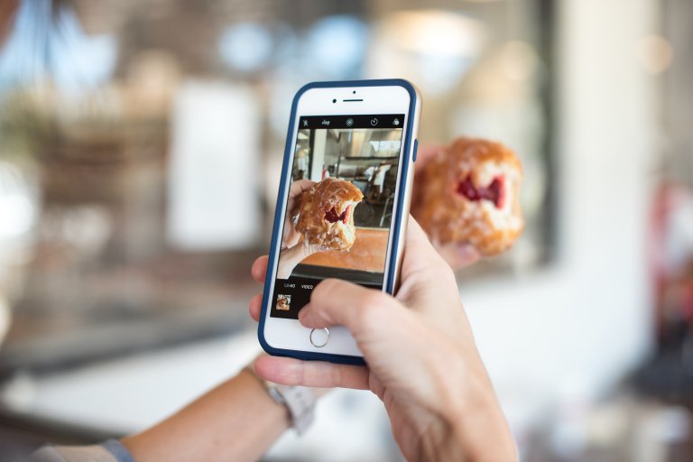 Bilde av en telefon som tar bilde av et bakverk. Bakgrunnen er uklar. Foto: Callie Morgan / Unsplash