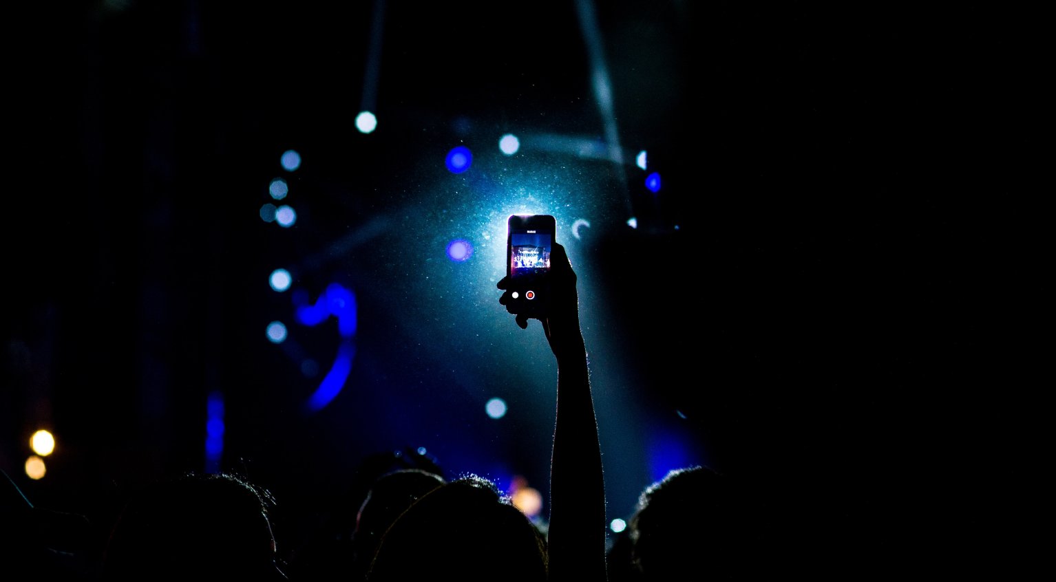 Illustrasjonsbilde. Mann som filmer konsert med mobilen