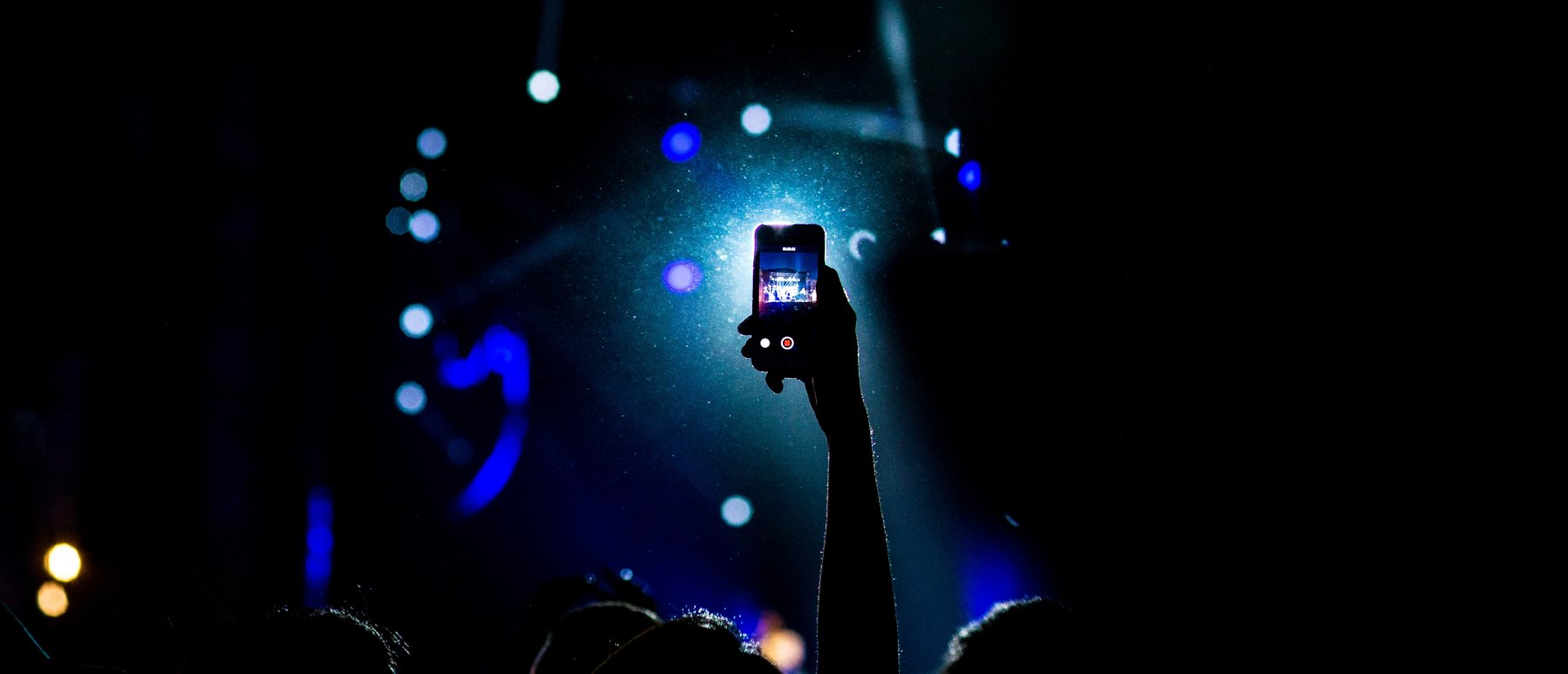 Illustrasjonsbilde. Mann som filmer konsert med mobilen