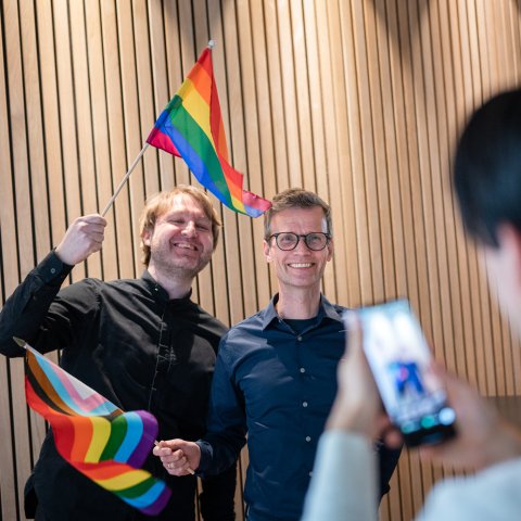 Portrett av Nils Petter Strømmen og Marius Jensen som vifter med regnbue-flagg.