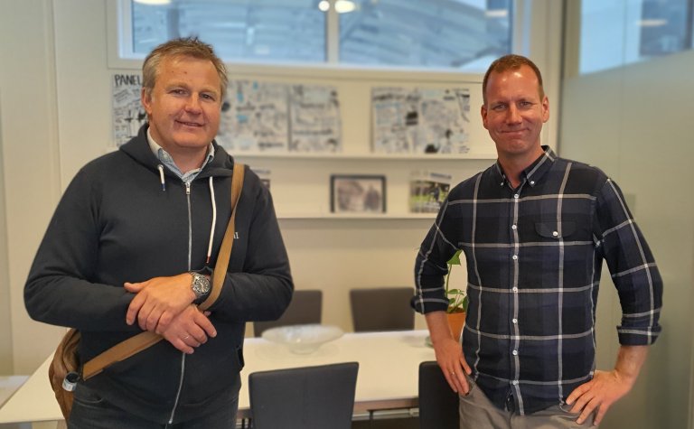 Eirik Andersen fra Ruter og Eirik Bergesen, programleder i Kommunikasjonspodden, står i kontorlokale.