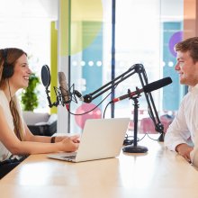 Ung kvinne intervjuer gjest i studio til en podkast