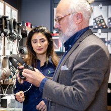 En Elgiganten ansatt hjelper en kunde med å velge headset.